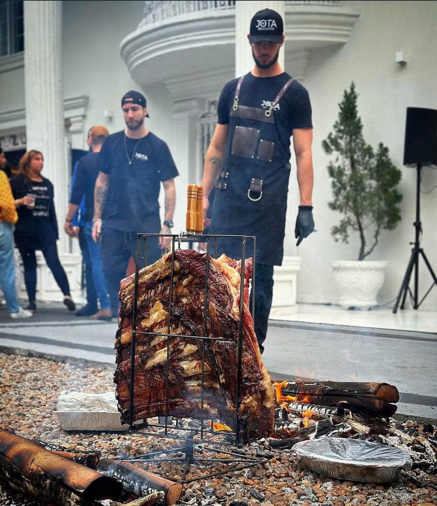 Jota Albuquerque preparando uma costela no assador de cruz sobre fogo aberto em evento